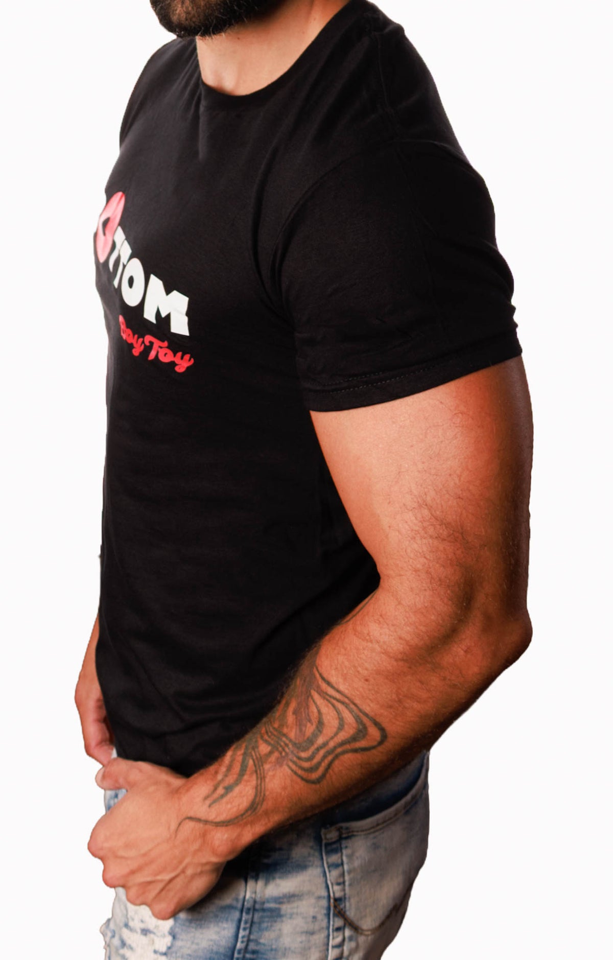 A man wearing a black short-sleeve t-shirt with a red and white graphic print on the chest, paired with light-wash distressed jeans, shown from a side profile against a white background.